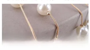 Detailed close-up of white round pearl and gold snake chain texture on necklace