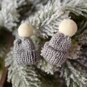Mini grey knitted Christmas hats with cream pom-poms for festive tabletop decoration