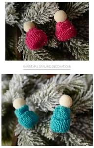 Close-up of mini knitted Christmas hats in red and blue on snowy pine branches