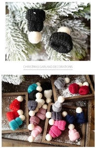 Close-up of mini knitted Christmas hats on pine branches and a wooden tray
