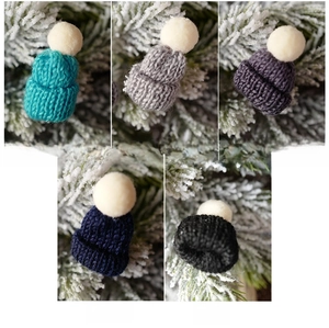 Detailed view of mini knitted Christmas hats in five colors with soft pom-poms