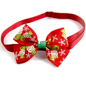 Detail of red Christmas ribbon bowtie with snowman pattern and green center for pets