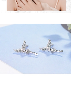 Macro detail of silver angel wing key earrings with sparkling zircon stones