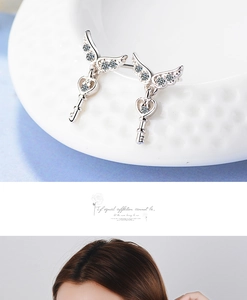 Macro view of silver angel wing key earrings with zircon inlay and heart detail