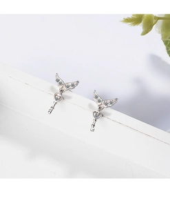 Macro shot of silver wing-shaped heart key earrings featuring detailed diamond inlay