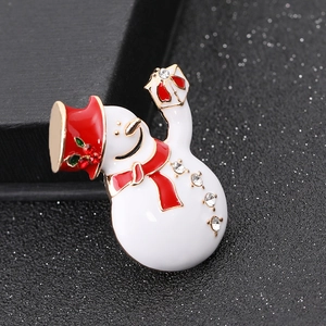 Detailed close-up of a snowman brooch with white enamel, red hat, and sparkling rhinestones