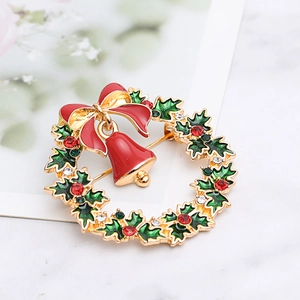 Close-up of a Christmas wreath brooch with a red bow and bell on a marble background