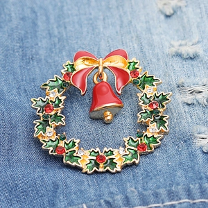 Close-up of a Christmas wreath brooch with red bow and bell on blue denim background