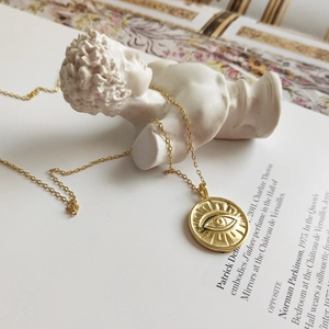 925 silver evil eye coin necklace on artistic plaster sculpture and fashion magazine