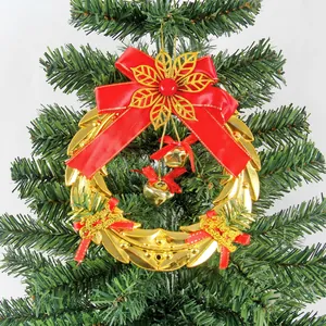 Golden Christmas bell wreath with red bow and Merry Christmas text on green tree branch