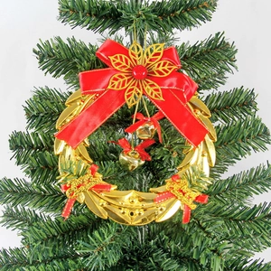 Close-up of golden Christmas wreath with red bow and bells hanging on a tree branch