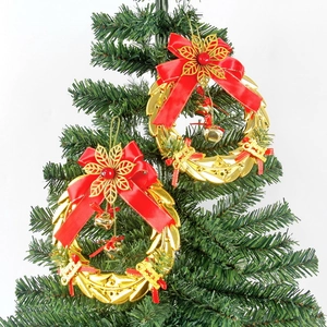 Detail of gold Christmas wreath hangers with red bows and bells on a festive tree branch