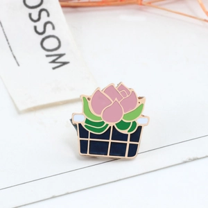 Detailed close-up of a lotus plant enamel brooch with pink petals and gold outlines