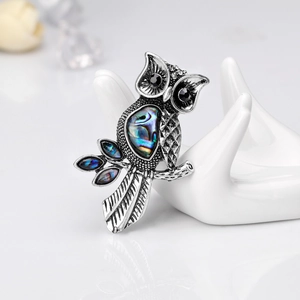 Vintage silver owl brooch with colorful natural abalone shell on a white hand display