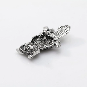 Macro shot of vintage owl brooch back showing silver metal pin and textured finish