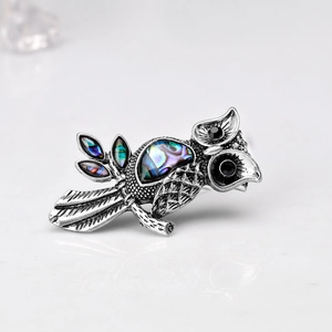 Detailed view of an owl brooch featuring abalone shell inlay and iridescent finish