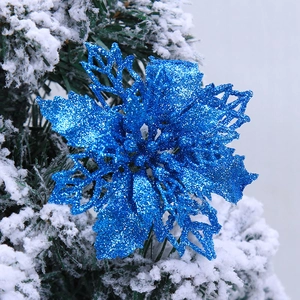 Sparkling blue glitter artificial Christmas flower decorating a snowy Christmas tree