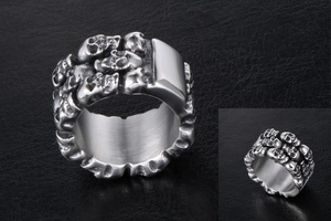 Detailed close-up of a silver stainless steel skull ring with embossed metal textures