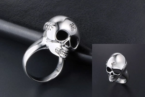 Macro shot of silver skull ring with cross engraving on dark textured background