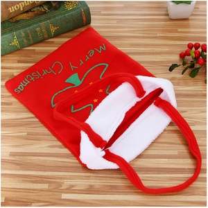 Sac cadeau de Noël en velours rouge avec broderie Merry Christmas sur table