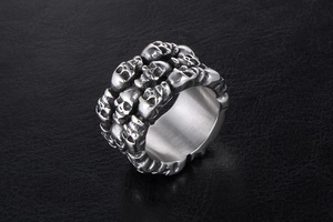 Close-up of wide skull head ring in stainless steel on dark textured leather background