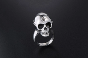 Macro shot of silver skull ring with cross engraving on forehead in punk style