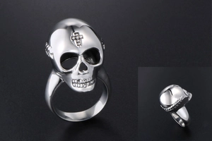 Macro detail of silver skull ring with cross engraving on vintage stainless steel surface