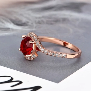Detail of rose gold halo ring with oval red gemstone and micro-pave zircon side stones