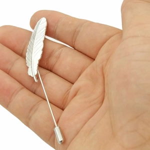 Detailed view of silver feather lapel pin with intricate textures and long needle clutch