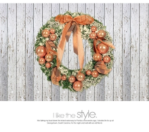 Detail of Christmas wreath with orange ornaments and large brown bow on wooden wall