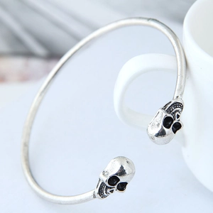 Close-up of vintage silver skull cuff bracelet resting on a white ceramic mug