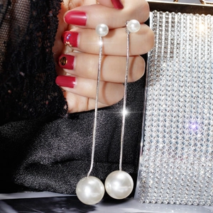 Long pearl drop earrings with silver snake chain worn by a model in luxury setting