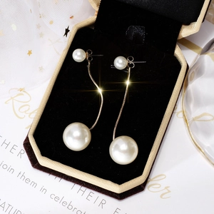 Close-up of elegant long gold pearl tassel earrings on black velvet jewelry box