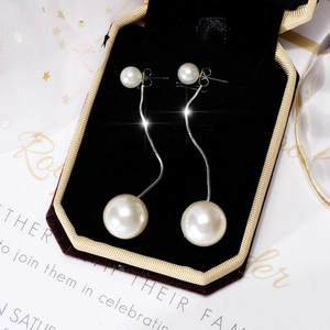 Detailed close-up of elegant long pearl tassel earrings in a black velvet jewelry box