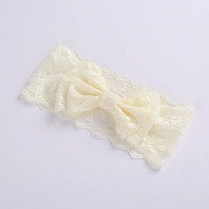 Close-up of beige lace baby headband featuring a double-layered bow on a white background