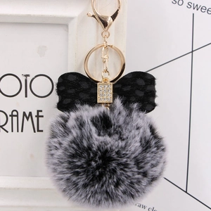 Detail of grey faux fur pompom keychain with polka dot bow and crystal center