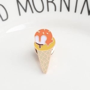 Detailed close-up of a colorful ice cream cone enamel pin on a white ceramic plate