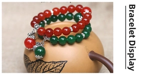 Detail of red and green round bead bracelets with silver flower charms on ceramic pot