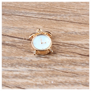 Golden vintage alarm clock charm pendant for DIY jewelry making on wood background