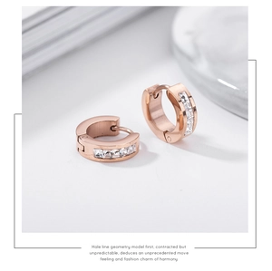 Macro detail of rose gold earrings with square zircon stones on marble surface