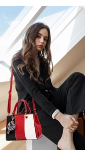Detail view of tri-color paneled handbag with crocodile texture and fur ball charm