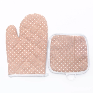 Pink polka dot cotton oven mitt and pot holder set with quilted texture on white background