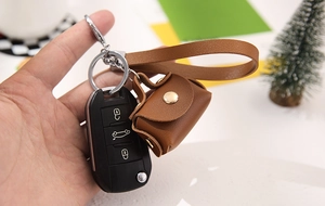 Detailed view of a brown leather wristlet keychain attached to a modern car key fob