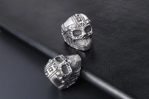 Detail of silver skull helmet rings on black leather showing punk metal craftsmanship