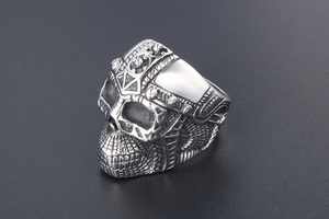 Detailed close-up of a silver punk skull ring featuring intricate metallic engravings