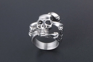 Macro shot of silver skull punk ring with detailed bone textures and polished finish