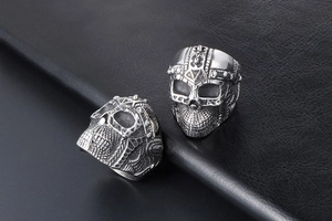 Detailed view of silver skull rings with punk style relief on black leather background