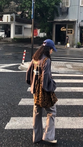 Street style view of a woman carrying a leopard print canvas tote bag with casual outfit