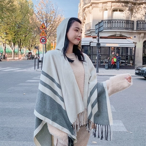 Detail of bohemian hooded shawl featuring blue-grey stripes and fringe tassels