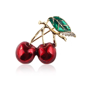 Minimalist red cherry brooch with green rhinestone leaf on a white background
